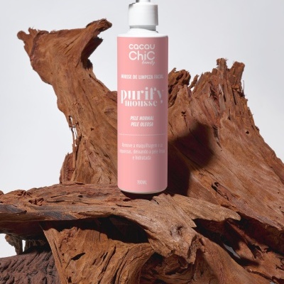 Frasco rosa de mousse de limpeza facial Cacau Chic Beauty sobre madeira