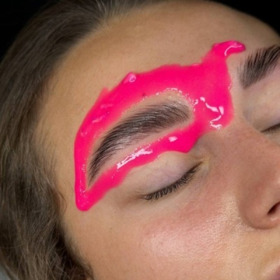 Máscara gel rosa claro delineando a sobrancelha de uma pessoa