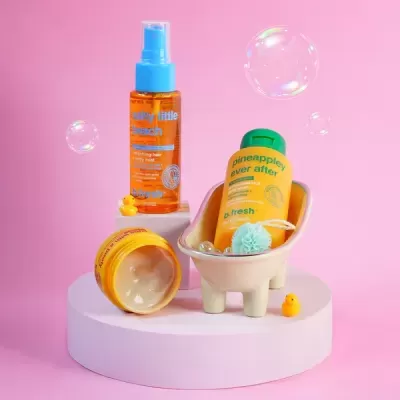 Produtos de cuidado pessoal b.fresh em mini banheira cerâmica com patos de borracha e bolhas em fundo rosa