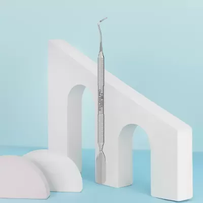 Instrumento metálico para cuidados podológicos entre blocos decorativos.