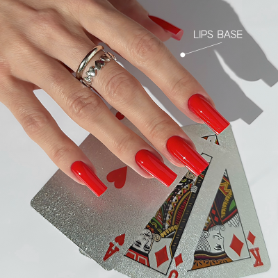 Mão com unhas vermelhas longas segurando cartas de baralho prateadas e anéis prateados