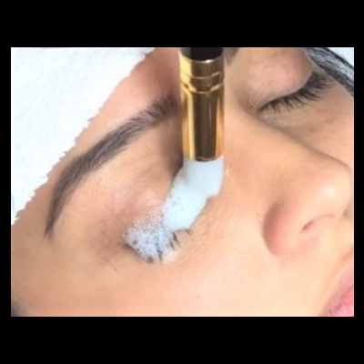 Aplicação de espuma branca com escova de maquilhagem dourada na área dos olhos