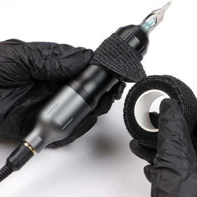 Máquina de tatuagem preta com fita adesiva preta nas mãos com luvas.