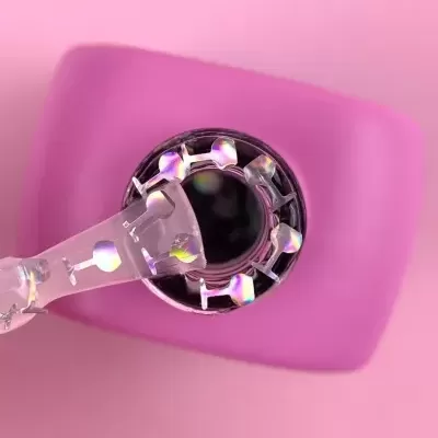 Frasco de verniz com tampa preta e pincel transparente sobre superfície rosa