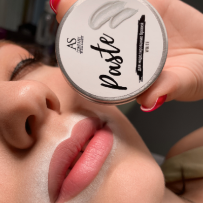 Pasta branca em embalagem redonda mostrada próxima ao rosto de uma pessoa