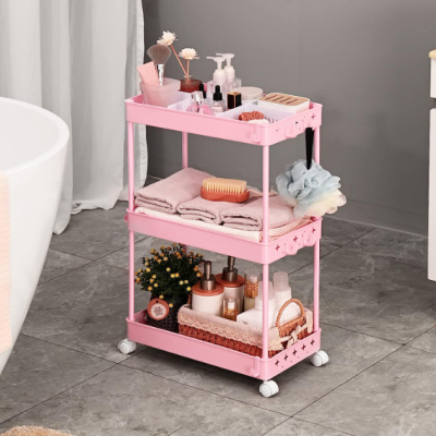 Carrinho organizador rosa com produtos de banho e toalhas sobre chão de azulejo cinzento