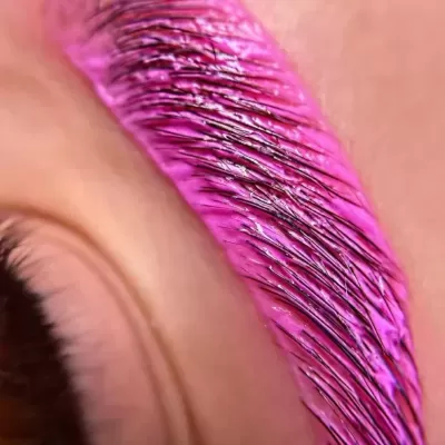 Sobrancelha pintada de rosa vibrante com textura brilhante em pele clara