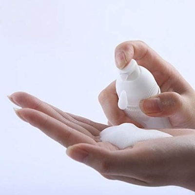 Mãos usando espuma de um frasco branco