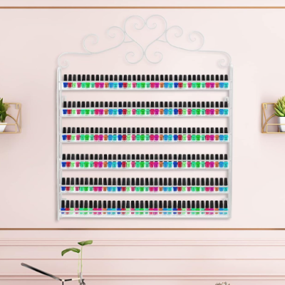 Expositor de vernizes de unhas com várias cores pendurado num parede cor de rosa claro