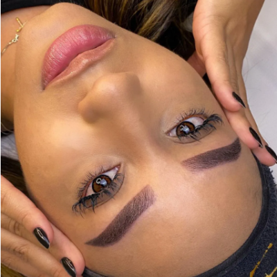 Rosto feminino visto de cima com sobrancelhas escuras e unhas pretas