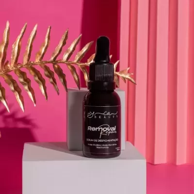 Frasco preto de sérum com conta-gotas e etiqueta preta em fundo rosa com base branca e folha dourada