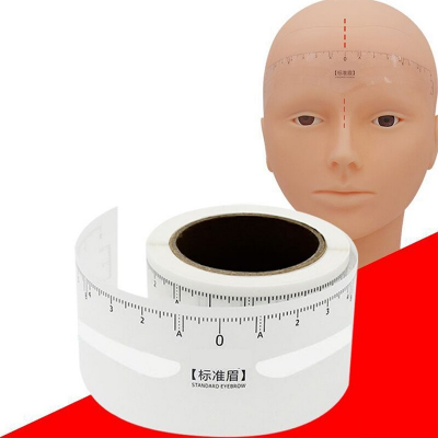 Rolo de régua adesiva branca para sobrancelhas ao lado de cabeça de manequim com medidas