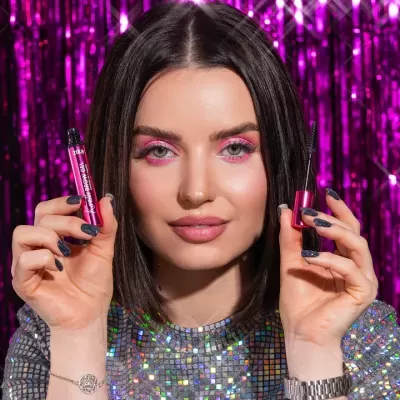 Mulher segurando um tubo e aplicador de gel para sobrancelhas Zola num fundo roxo brilhante