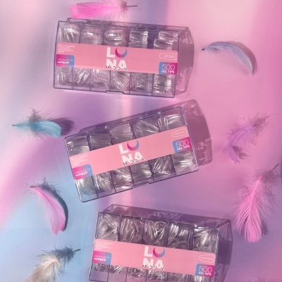 Caixas de gel tips transparentes com etiquetas rosas sobre fundo azul e rosa com penas coloridas