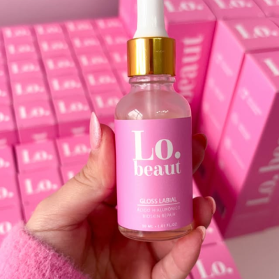 frasco de gloss labial rosa com tampa branca e detalhe dourado