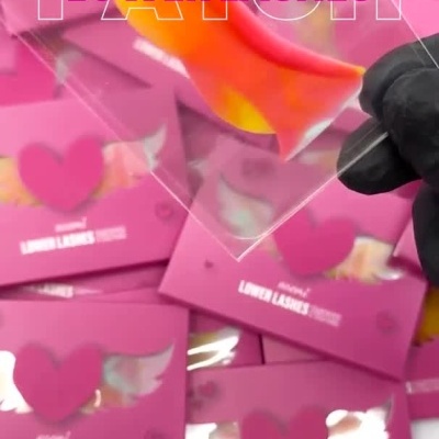 Caixa rosa de patch para pestanas inferiores noemi LOWER LASHES PATCH com aplicação do patch em tons laranja e vermelho abaixo do olho.