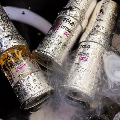 Três frascos de cosméticos Zola com gotas de água e fundo escuro