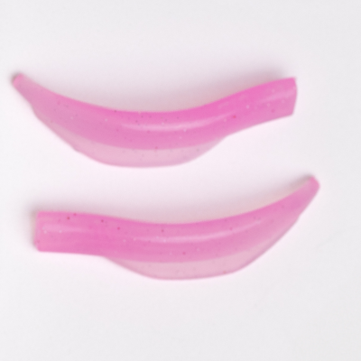 Dois pedaços de plástico rosa translúcidos com brilho, forma curva, fundo branco