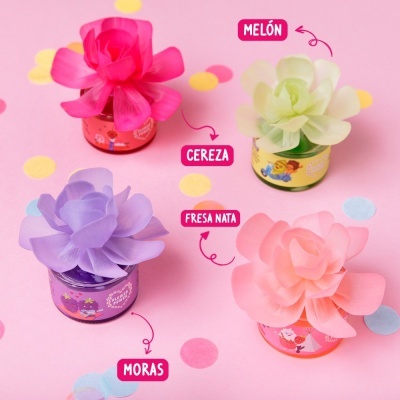 Quatro frasquinhos coloridos com flores de tecido e rótulos com nomes de sabores sobre fundo rosa com pontos coloridos