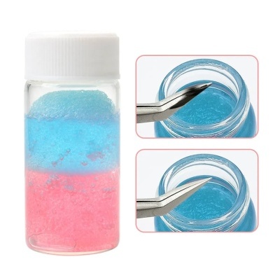 Frasco com gel azul e rosa e pinças tóçando o gel azul