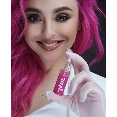 Pessoa com cabelo rosa segura frasco rosa de produto cosmético zói? HENNA