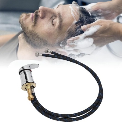 Torneira cromada com mangueiras e homem a lavar cabelo com espuma