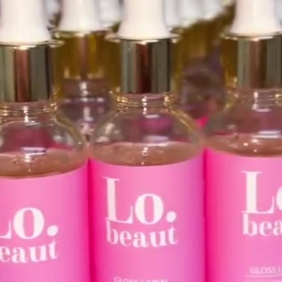 Frascos de gloss labial com rótulo rosa e conta-gotas branco e dourado