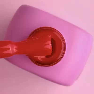 Verniz de unhas vermelho com pincel sobre fundo rosa