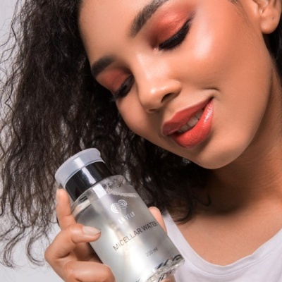 Mulher com maquilhagem segura garrafa de água micelar 200 ml
