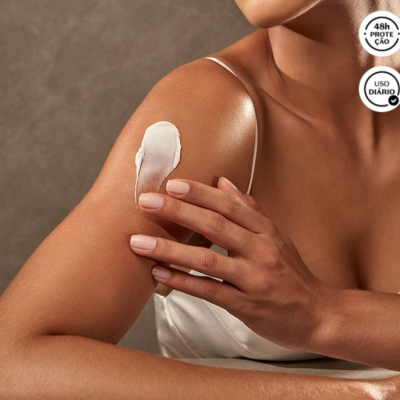 Mulher aplicando creme branco no ombro com textos 48h PROTEÇÃO e USO DIÁRIO