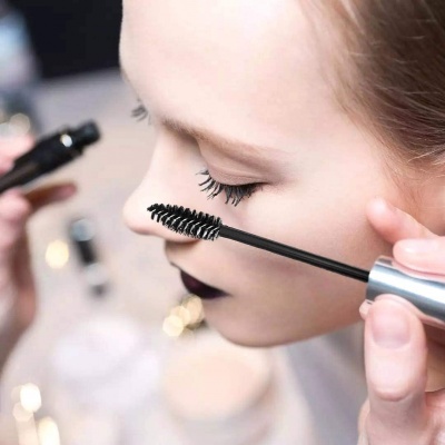 Pessoa com pincel de máscara de pestanas a aplicar maquilhagem