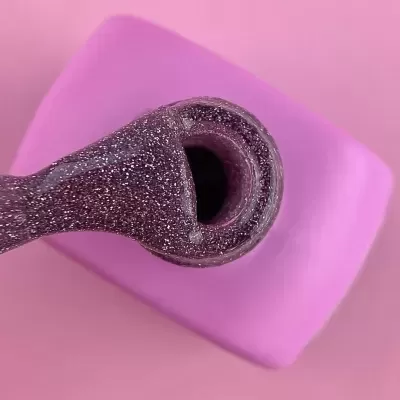 Pincel de verniz de unhas roxo brilhante com glitter aberto em frasco rosa