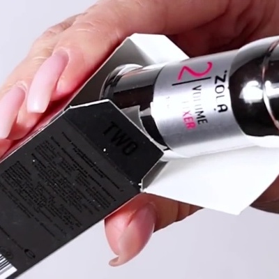 Pessoa a mostrar o frasco prateado do Zola Brow & Lash Lamination System 2 Volume Fixer.