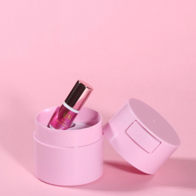 batom líquido rosa com tampa metálica numa caixa cilíndrica rosa sobre fundo rosa