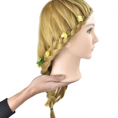 Cabeça de manequim com cabelo loiro trançado e flores decorativas, sendo segurada por uma mão