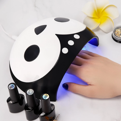 Lâmpada de cura para unhas em forma de panda com mão feminina sob luz azul