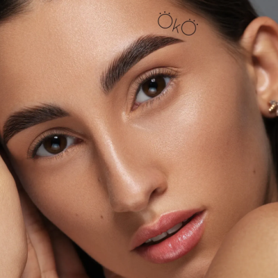 Rosto de mulher com maquilhagem natural e sobrancelhas definidas com texto ÖKÖ na testa