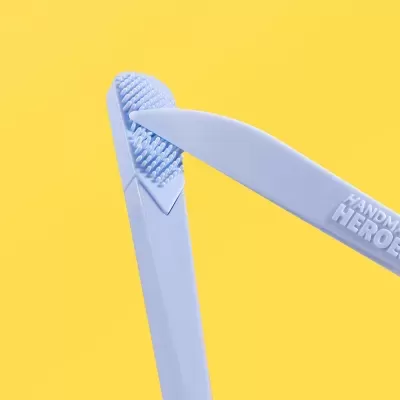 Ferramentas plásticas azuis com textura e texto em relevo HANDMA HEROE, fundo amarelo