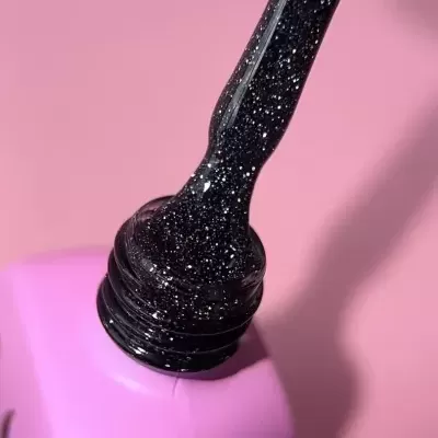 Pincel de esmalte preto com brilhos a sair de frasco cor-de-rosa