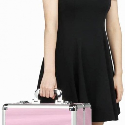 Mulher com vestido preto segurando mala rígida rosa e prateada.