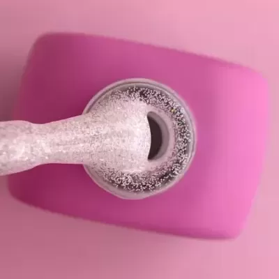 Frasco de verniz rosa claro com glitter e tampa rosa visto de cima