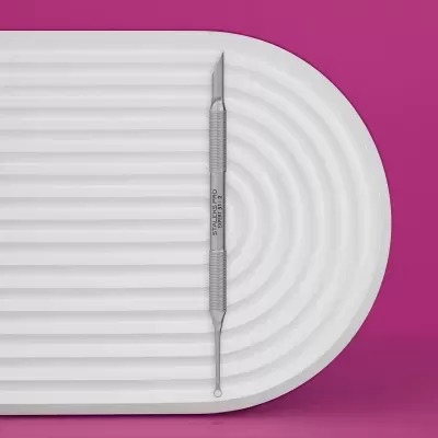 Ferramenta de cuidados de pele de aço inoxidável sobre superfície branca e fundo rosa