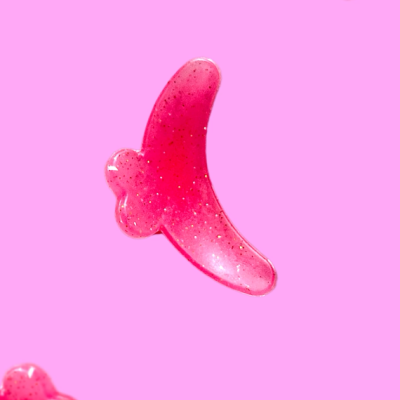 Gel rosa translúcido em forma de banana sobre fundo cor-de-rosa