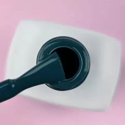 Frasco de verniz preto aberto com pincel sobre fundo rosa