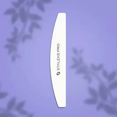 Lima de unhas branca curva STALEKS PRO sobre fundo lilás com sombras de folhas