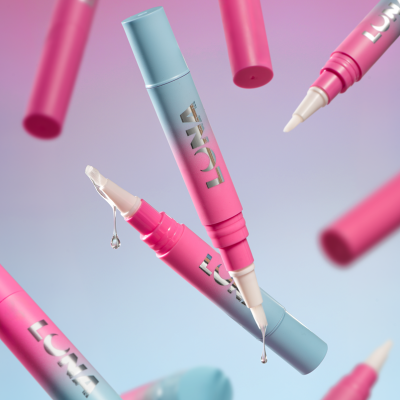 Canetas cosméticas cor-de-rosa e azul com pincéis e gotas em fundo colorido