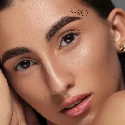 Rosto de mulher com sobrancelha espessa e texto 'ÖKÖ' acima da sobrancelha direita