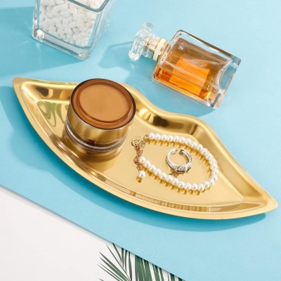 Bandeja dourada em forma de lábio com creme, perfume e joias