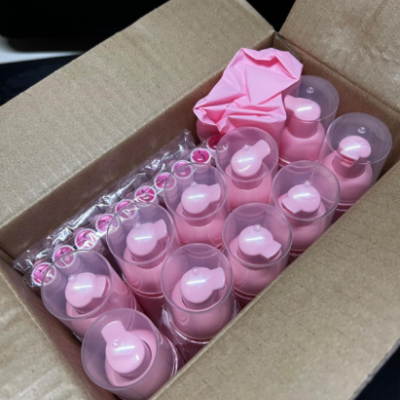 Frascos plásticos rosa com tampas transparentes dentro de caixa de cartão