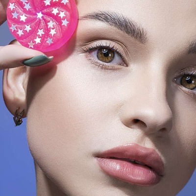 Mulher com disco rosa translúcido e estrelas brancas junto ao rosto